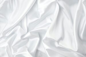 Creases of white satin, silk, and cotton. Abstract white fabric texture background. Cloth soft wave