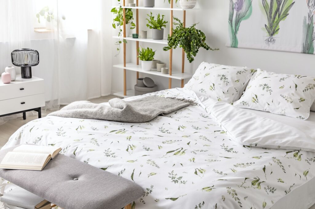 Green plant pattern on white bedding and pillows on a bed in a n